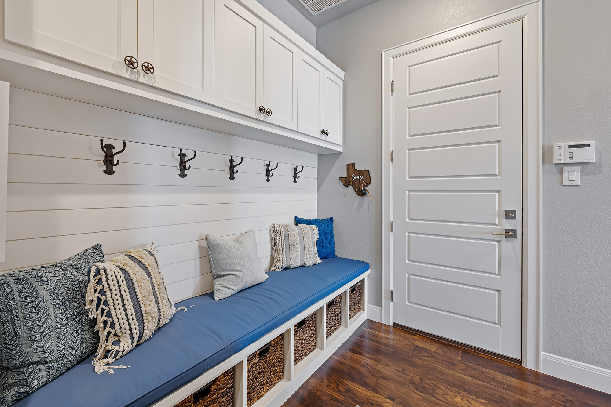 Dark brown hardwood flooring in a bright mudroom with built in bench